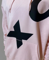 Gros plan sur le monogramme XC noir et la poche kangourou du Hoodie XC Indar rose